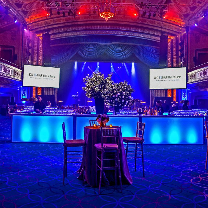 A spacious room illuminated by blue lighting, featuring several tables arranged throughout the area.